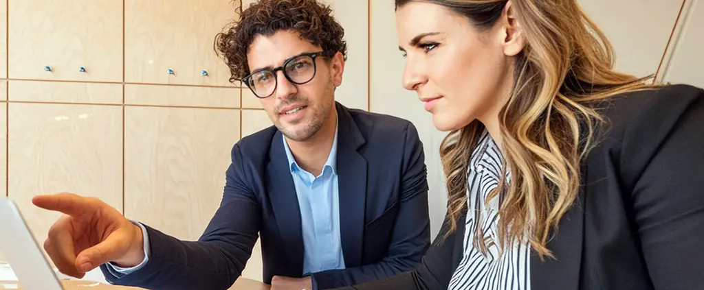 Franchise coordinator working with franchise recruiter on a computer.